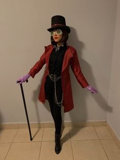 a woman dressed up in a red coat and black top hat with purple gloves holding a cane