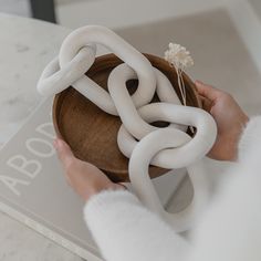 a person holding a wooden bowl with large white rings on it's sides and a flower in the middle