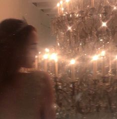 a woman standing in front of a chandelier