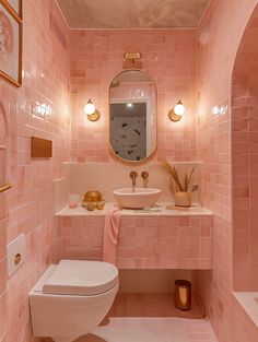 a bathroom with pink tiled walls and flooring, including a white toilet and sink