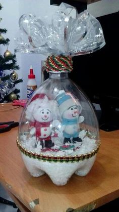 an ornament in the shape of a glass bottle with two snowmen inside