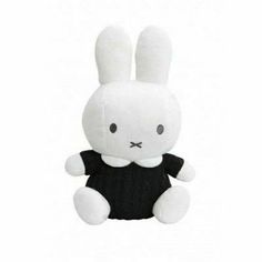 a white stuffed rabbit sitting on top of a white floor next to a black and white wall