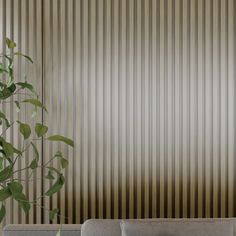 a white couch sitting next to a plant in front of a wall with vertical blinds