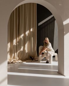 a woman sitting on a chair in front of a curtain