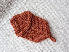 an orange knitted hat laying on top of a white blanket