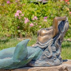 a statue of a mermaid laying on top of a rock