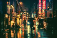 people are walking down the street in the rain at night with umbrellas and signs