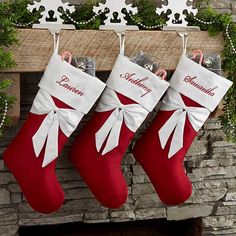 three stockings hanging from a mantel decorated with greenery and bows, along with the word grandma written on them