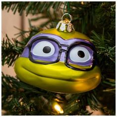 an ornament shaped like a frog with glasses on it's face hanging from a christmas tree