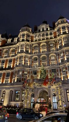 a large building with christmas lights on it's side and cars parked in front