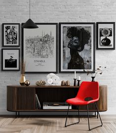 a red chair sitting in front of a wooden table next to pictures on the wall