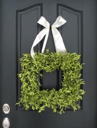 a black door with a wreath and white ribbon on it