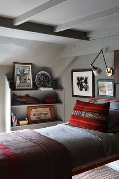 a bed sitting in a bedroom next to two shelves filled with pictures and other items