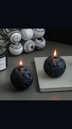 two black candles sitting on top of a white plate