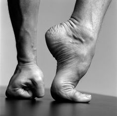 black and white photograph of a person's bare feet on a wooden table top