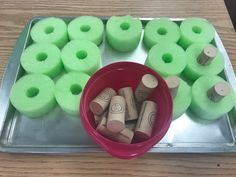 several rolls of toilet paper are in a red bowl on a metal tray with green felt