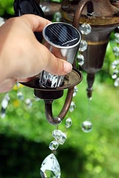 a person holding an object in their hand with bubbles coming out of it and the words, replace the light bulbs in an old chandelier with expensive solar lights hang from a tree branch