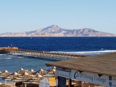 an ocean view with umbrellas and mountains in the background