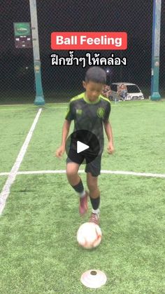 a young boy kicking a soccer ball on top of a green field with an advertisement in the background