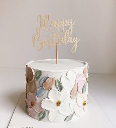 a birthday cake decorated with flowers and the words happy birthday written on top in gold