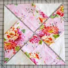 a quilted piece of fabric with flowers on it sitting on top of a cutting board