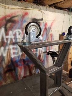 a metal table with wheels on it in front of a graffiti covered wall and floor