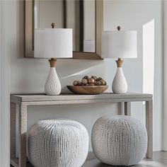 two white vases sitting on top of a wooden table