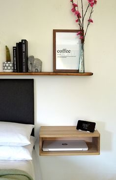 a bed room with a neatly made bed and a shelf on the wall above it