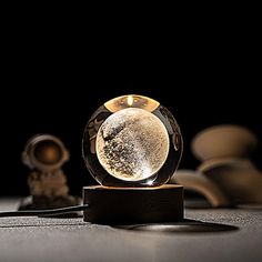 a glass ball sitting on top of a wooden stand next to a small figurine