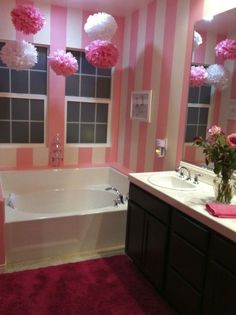 a bathroom decorated in pink and white with flowers on the bathtub, vanity mirror, and two sinks