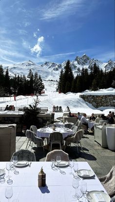 an outdoor dining area with tables, chairs and snow covered mountains in the back ground