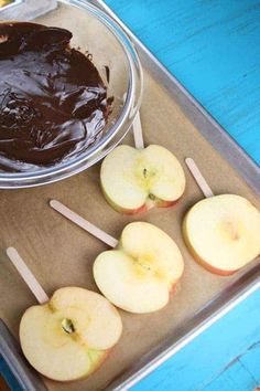 there are apples and chocolate on the tray with sticks in front of them, ready to be eaten