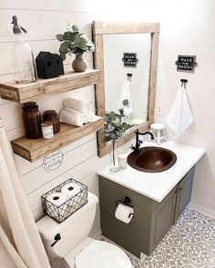 a white toilet sitting next to a bathroom sink under a mirror above a wooden shelf