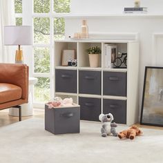 a living room scene with focus on the storage unit and stuffed animals in the foreground