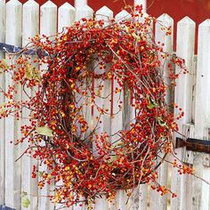 a wreath with red berries hanging on a white fence