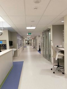 an empty hospital hallway with medical equipment on the walls and desks along one side