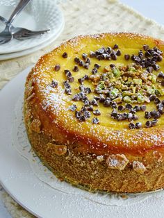 a cake sitting on top of a white plate covered in nuts and other toppings