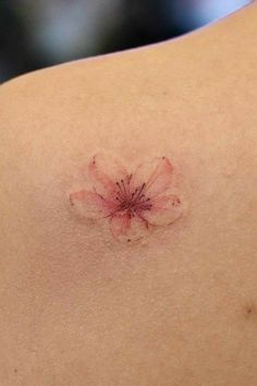 a small flower on the back of a woman's shoulder