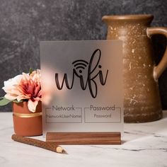 a sign that says wifi next to a vase with flowers and a pencil on it