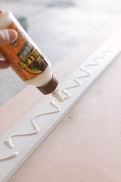 someone is painting the letters white on a wooden table