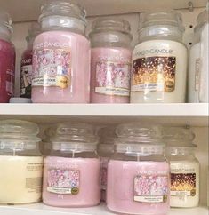 candles are lined up on shelves in a store, one is pink and the other is white