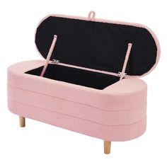 a pink ottoman with an open lid and wooden legs