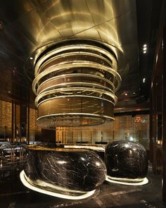 the interior of a restaurant with marble tables and stools in front of a circular chandelier