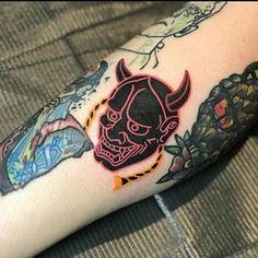 a person with a tattoo on their arm has a red devil and other things in the background