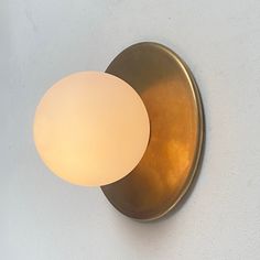 a light that is on the wall next to a white wall with a round glass shade