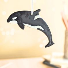 a black and white ornament hanging from a string with a dolphin on it