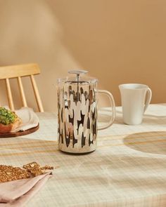 a coffee pot sitting on top of a table next to a plate with food in it