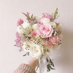 a person holding a bouquet of pink and white flowers