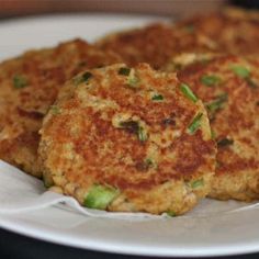 three crab cakes on a white plate ready to be eaten with sauce and seasoning