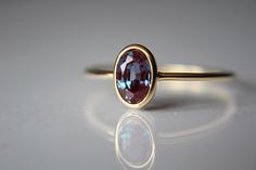 This lovely Lab-Created oval 6x4mm Alexandrite ring has a rich, romantic feel to it. I have set this 6x4mm stone into a solid 14k bezel cup. The 18 gauge band has been also highly polished for a very reflective shine to add to this sparkly stone. This style ring has an open back to allow light to pass through the stone. Material Information: Clarity: Occlusion free Color: Green, blue, purple Gemstone: Lab-Created oval 6x4mm Alexandrite  Metal: 14k yellow gold ★ IMPORTANT SHIPPING & PRODUCTION DE Oval Alexandrite Ring, Elegant Oval Ruby Ring With Bezel Setting, Elegant Oval Bezel Set Birthstone Ring, Oval Sapphire Ring In Yellow Gold For Proposal, Oval Ruby Ring With Bezel Setting For Wedding, Elegant Oval Ruby Ring For Proposal, Oval Bezel Set Engagement Ring, Stacked Rings Aesthetic, Alexandrite Rings